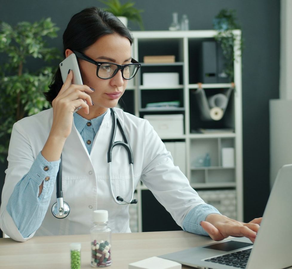 Une médecin parle au téléphone devant son ordinateur