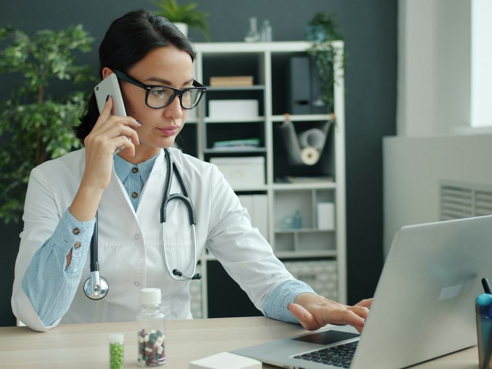 Une médecin parle au téléphone devant son ordinateur