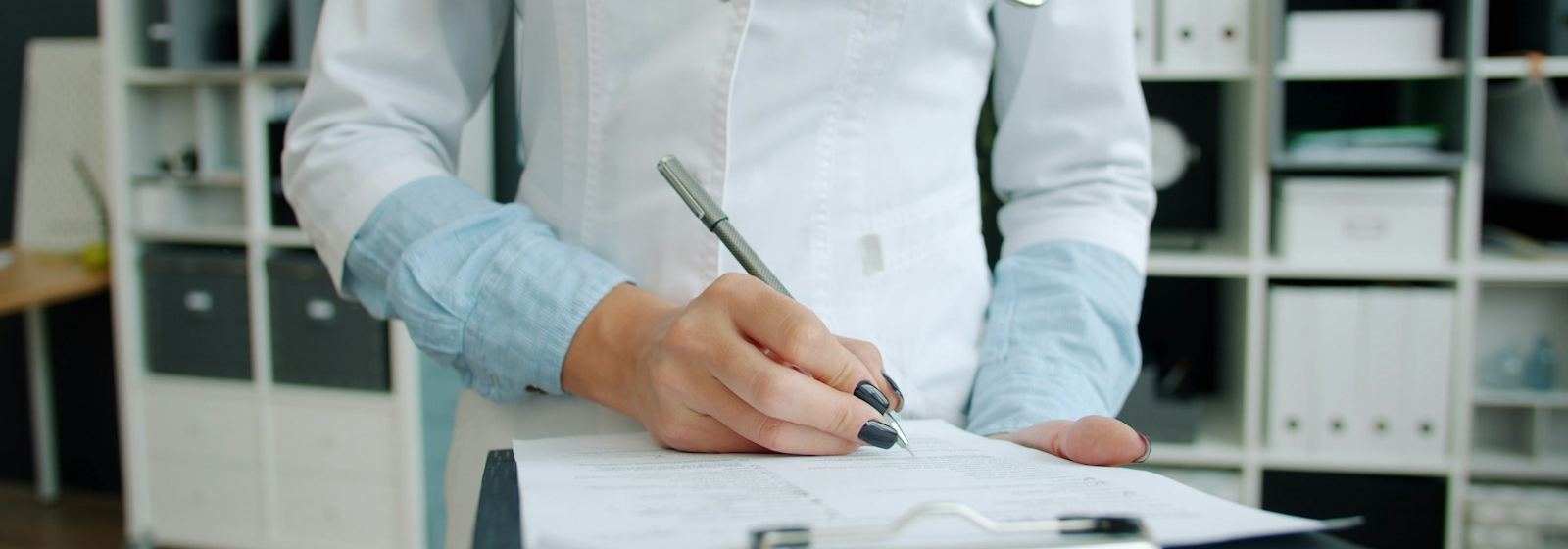 Un médecin prend des notes à la main sur un porte-bloc